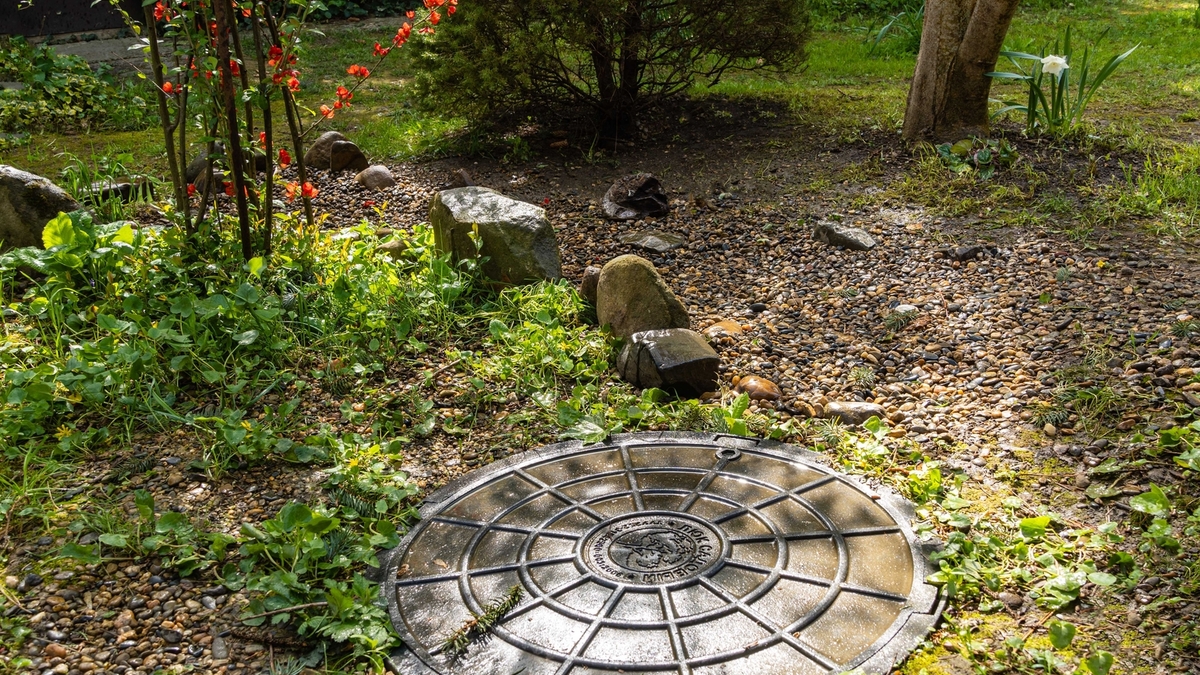 Système d'égout pour l'enlèvement de l'eau purifiée de la fosse septique sur une parcelle personnelle. Le champ de filtration de la fosse septique est recouvert de gravier et décoré de pierres et de plantes.