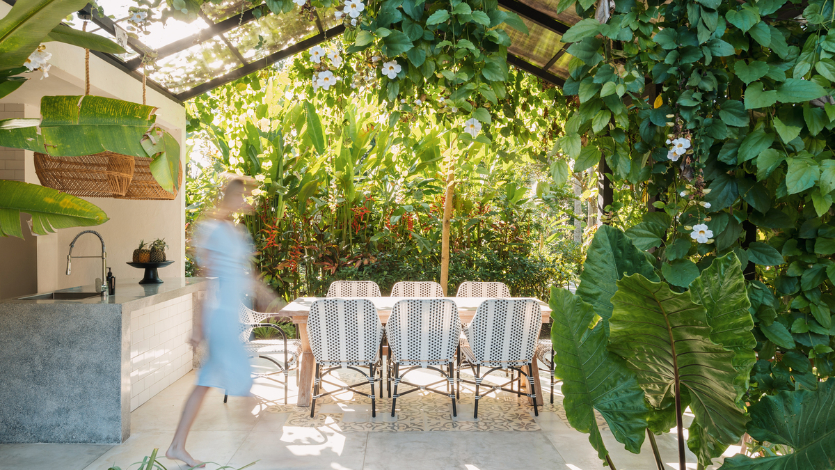 Sous une pergola végétalisée, cette cuisine d'été en pierre prolonge un coin repas pour une dizaine de convives.
